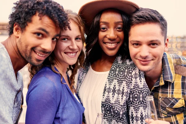 Multi-ethnic millenial group of friends taking a selfie photo with mobile phone on rooftop terrasse at sunset — стоковое фото