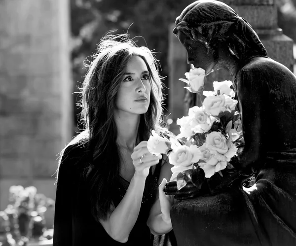 Женщина в кладбище, вручающая цветы любил один монохромный — стоковое фото