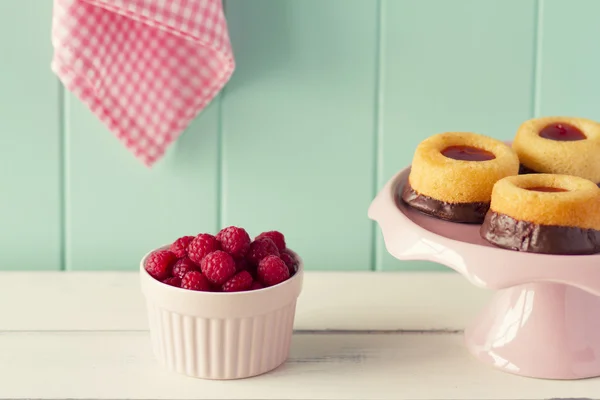 Малина и шоколадные торты и несколько свежая малина в розовый фарфорово выпечки чашу на белый деревянный стол с Робин яйцо синий фон и розовые клетчатые салфетку. Винтажный вид — стоковое фото