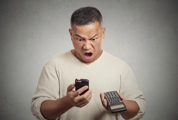 Потрясенный человек, считающий калькулятор смартфона, чувствующий отвращение к финансовым законопроектам — стоковое фото