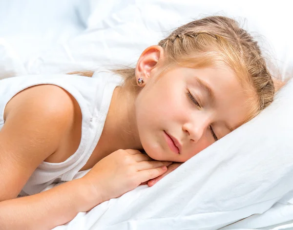 Маленькая девочка спит в белой кровати — стоковое фото