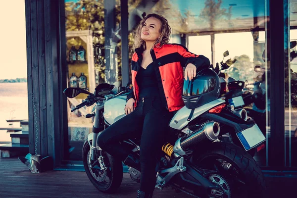 Блондинка женщина позирует возле мотоцикла Стоковое Изображение