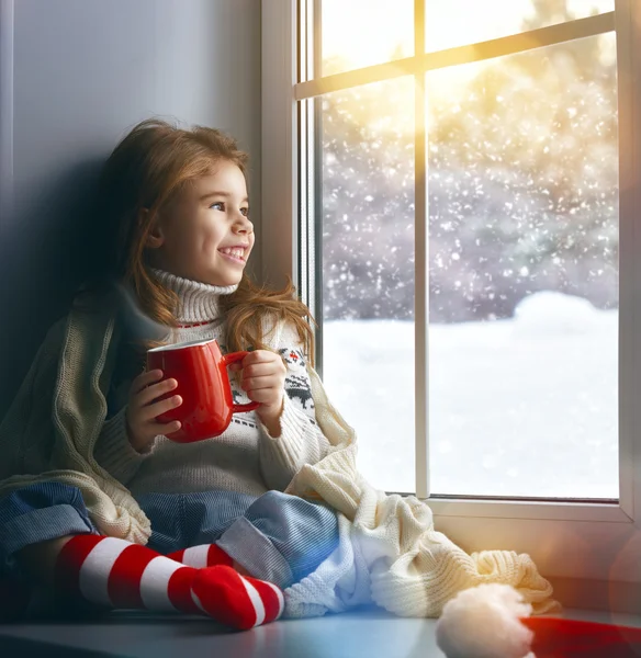 Маленькая девочка, сидящая у окна — стоковое фото