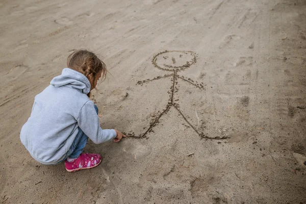Маленькая девочка песка рисует смешной человек — стоковое фото
