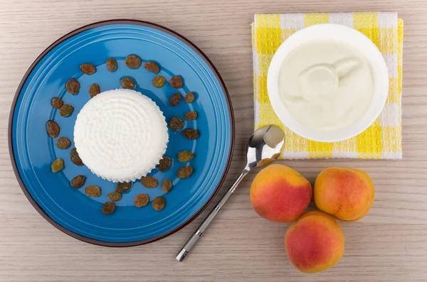 Творогом и изюмом в синюю тарелку, сметана и персики — стоковое фото