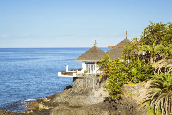 Хижины с соломенными крышами на краю скалы на берегу моря, стоимость — стоковое фото