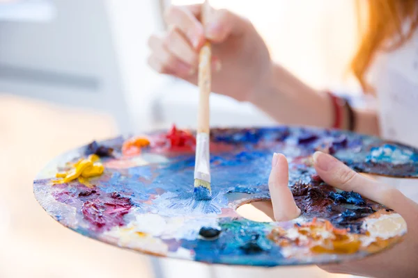 Paintbrush в руках женщины смешивая краски на палитре — стоковое фото