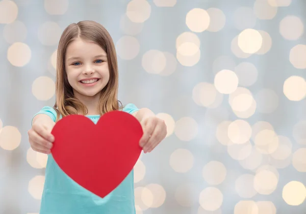 Улыбается маленькая девочка с красным сердцем — стоковое фото