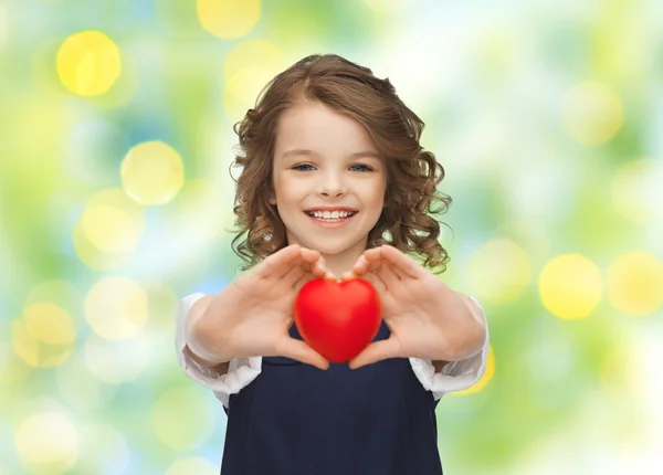 Улыбается маленькая девочка с красным сердцем — стоковое фото