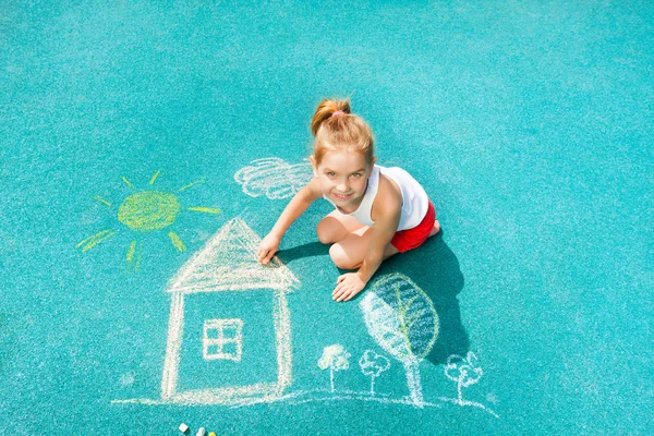 Маленькая девочка рисует мелом дом — стоковое фото