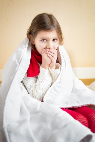 Больная маленькая девочка, кашляющая на кровати под одеялом — стоковое фото