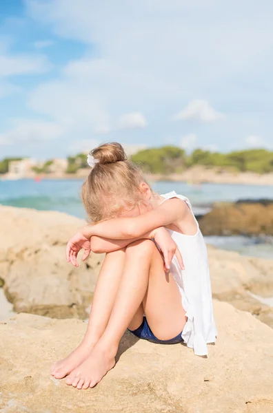 Грустно маленькая девочка сидит на пляже. Место для текста — стоковое фото