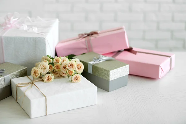 Декорированой подарочной коробки и букет роз на фоне белого кирпича стены — стоковое фото