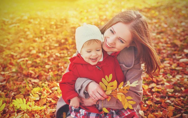 Счастливая семья: мать и ребенок мало играть дочь обнимаются на осень — стоковое фото