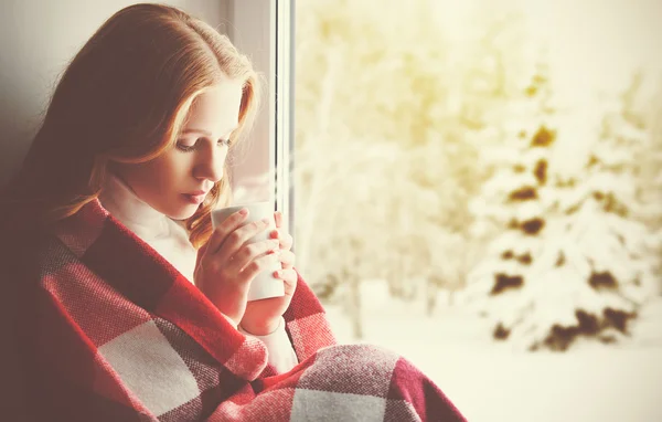 Задумчивый Грустная девушка с бокалом потепления, глядя в окно, в — стоковое фото