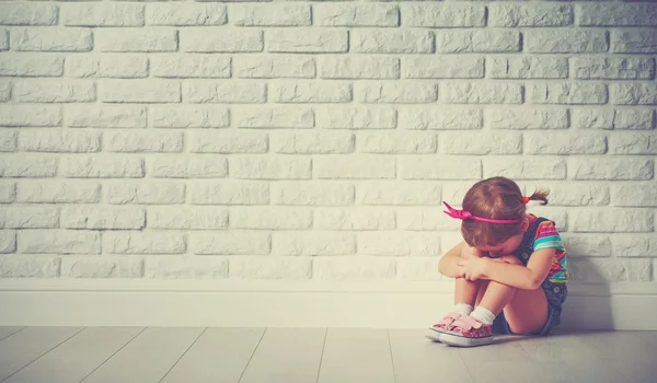 Маленькая девочка ребенок плачет и грустно о кирпичную стену — стоковое фото