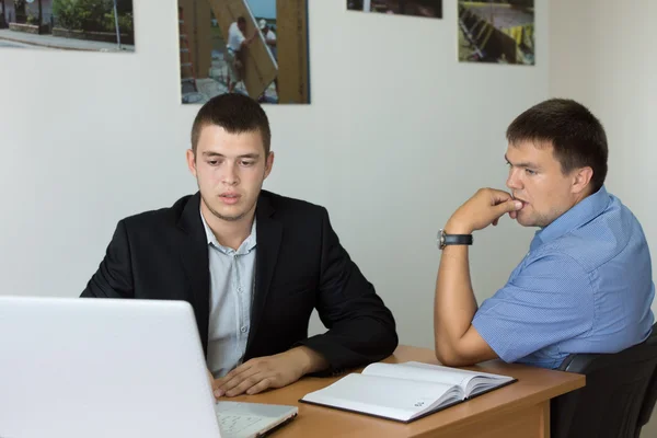 Молодые бизнесмены, смотрящие на компьютер серьезно Лицензионные Стоковые Изображения