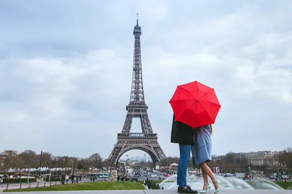 Пара целовать за красный зонт — стоковое фото