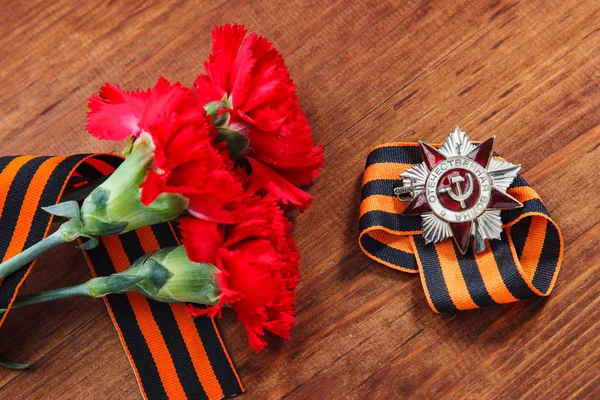 Орден Отечественной войны 1-го класса и две красные гвоздики. День победы. 9 мая. выборочный фокус изображения — стоковое фото