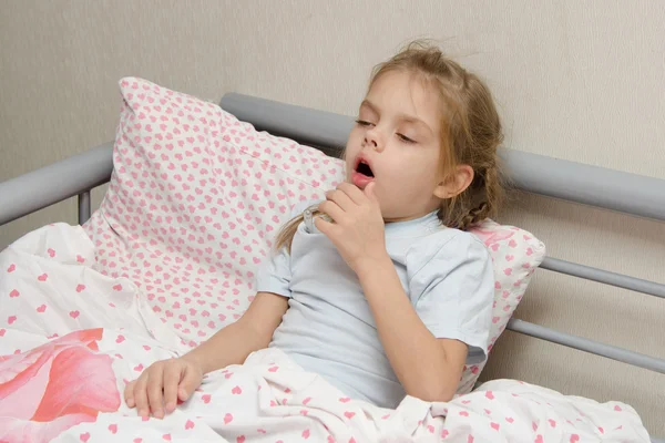 Больной девочкой, лежа в постели кашель — стоковое фото