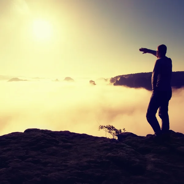 Человек в рубашке и джинсах стоит на вершине империи песчаника и смотрит на долину туманный и туманное утро солнце. Красивый момент чудо природы Лицензионные Стоковые Фото