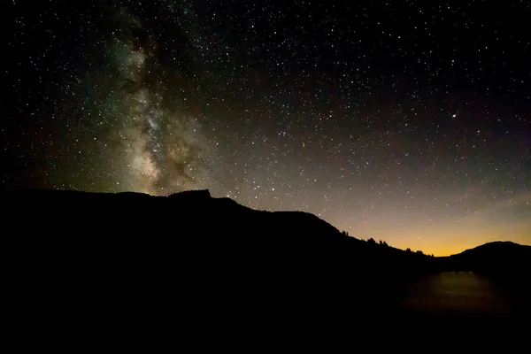 Млечный Путь выше черный силуэт горы с закат свечения ре — стоковое фото