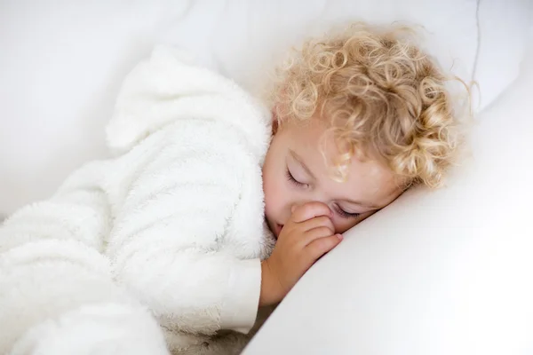 Cute blond curly little boy sleeping on white couch — стоковое фото