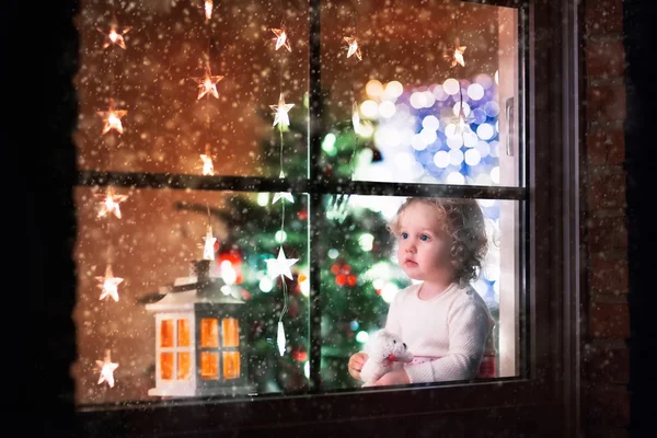 Маленькая девочка, сидя у окна в канун Рождества — стоковое фото