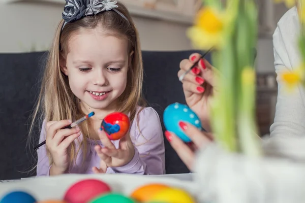 Праздник Пасха, семьи, и ребенок концепции - заделывают маленькой девочки и мать окраски яиц на Пасху Стоковая Картинка