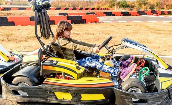 Маленькая девочка является движущей Go - Kart автомобилей в игровую площадку, гоночная трасса Лицензионные Стоковые Фото