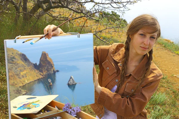 Художник женского пола привлекает горное побережье — стоковое фото
