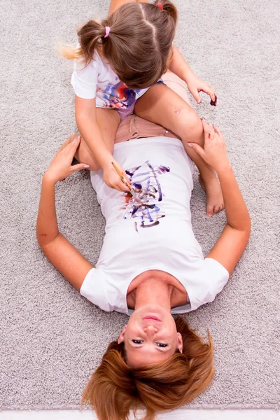 Девушка рисует краски на футболку мать на полу — стоковое фото