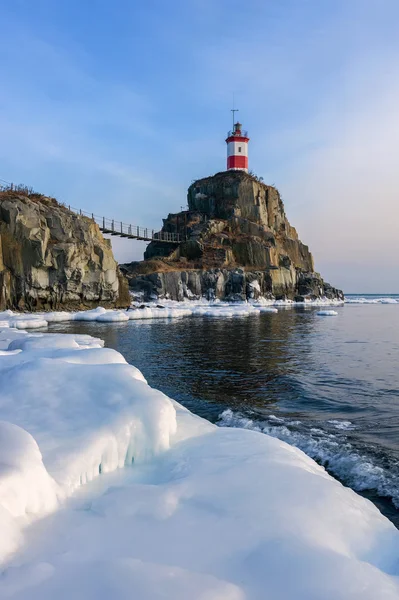 Зимний картинный маяк на одинокой скале Лицензионные Стоковые Фото