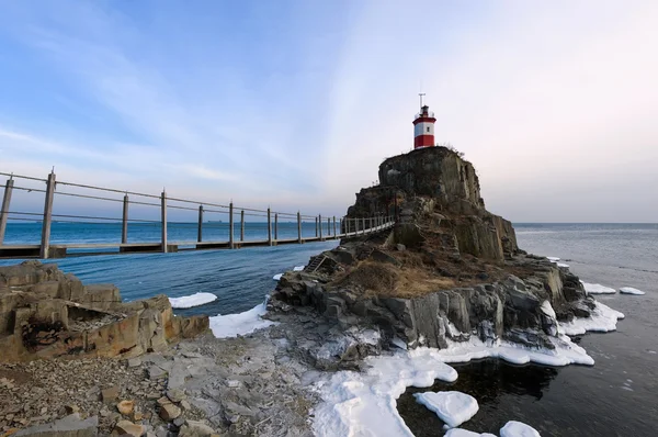 Зимний картинный маяк на одинокой скале Стоковое Изображение