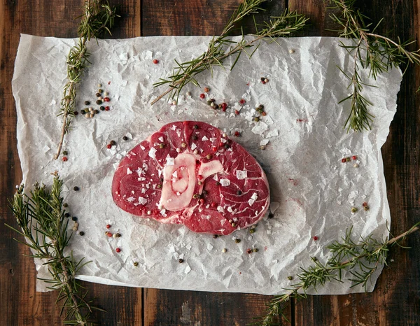 Top view meat steak with bone on craft paper; salted — стоковое фото