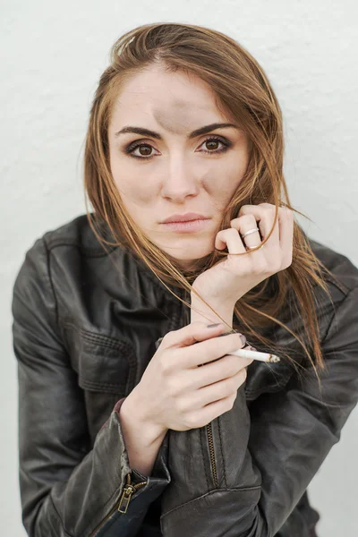 Грустно Длинношерстная девочка в кожаной куртке с сигаретой — стоковое фото