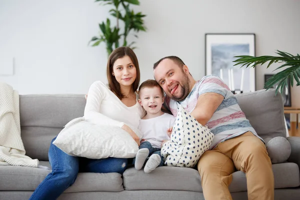 Счастливые родители с сыном на сером диване фото — стоковое фото