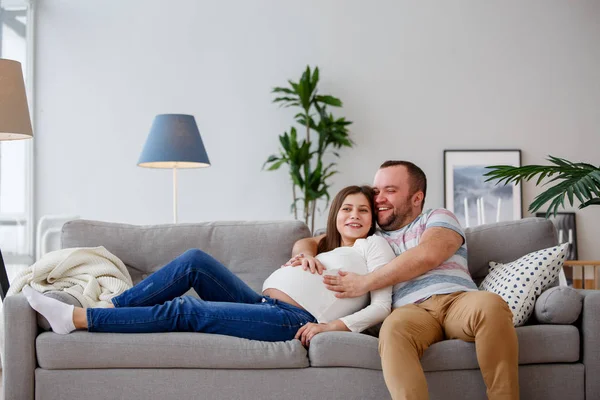 Изображение счастливой будущих родителей, сидя на серый диван — стоковое фото