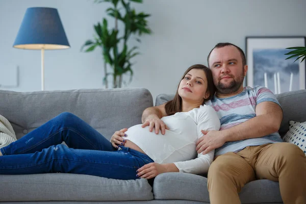 Фото беременной женщины и мужчины на сером диване — стоковое фото