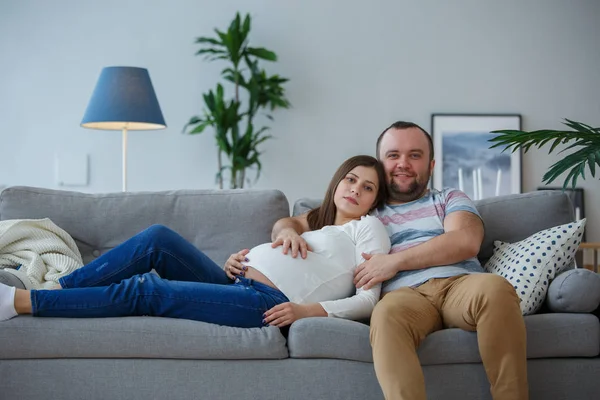 Картина Счастливый беременная женщина и мужчина на сером диване — стоковое фото