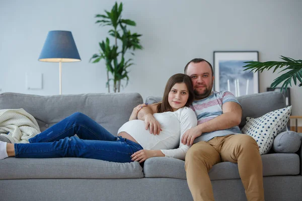 Фото счастливый беременная женщина и мужчина на сером диване — стоковое фото