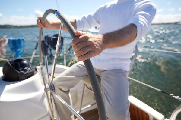 Старший мужчина у руля на парусные лодки или яхты в море — стоковое фото