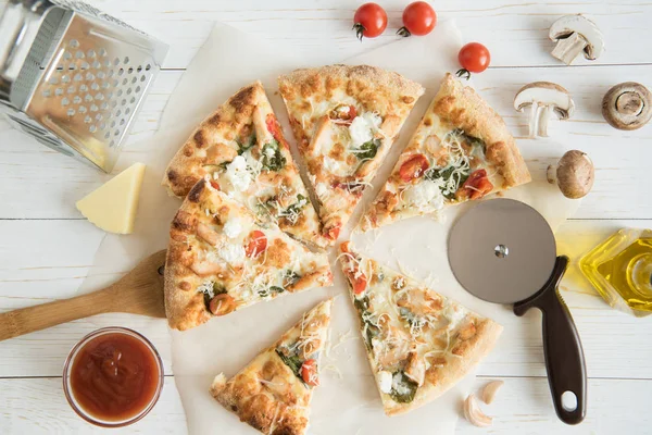 Нарезанная пицца с сыром и кухонной утварью — стоковое фото