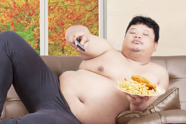 Ленивый толстый человек смотрит телевизор осенью — стоковое фото