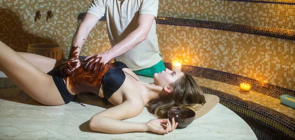 Сексуальная женщина на спа салон шоколадный массаж с мужской руки — стоковое фото
