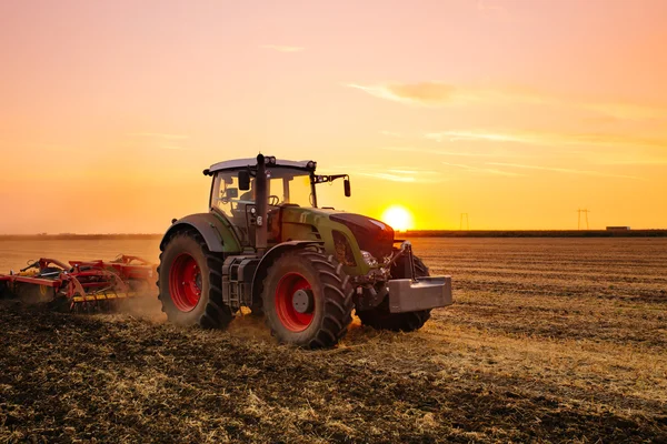 Трактор вспашки во время заката — стоковое фото