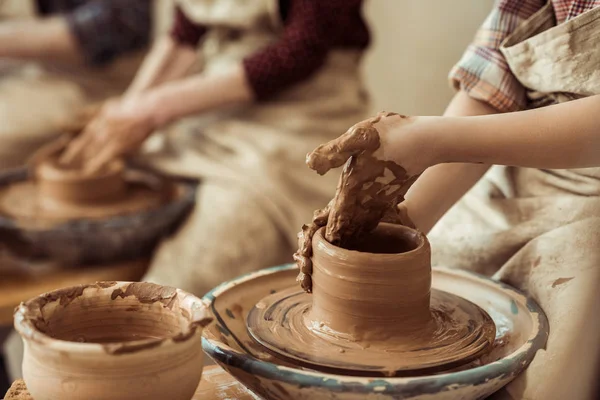 Закройте руки ребенка, работающие на гончарном колесе в мастерской — стоковое фото