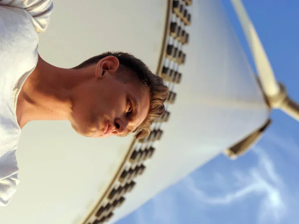 Вид из ниже прохладной молодой парень. Подросток, опираясь на Электрические мельницы. Стильный мужчина на фоне голубого неба — стоковое фото