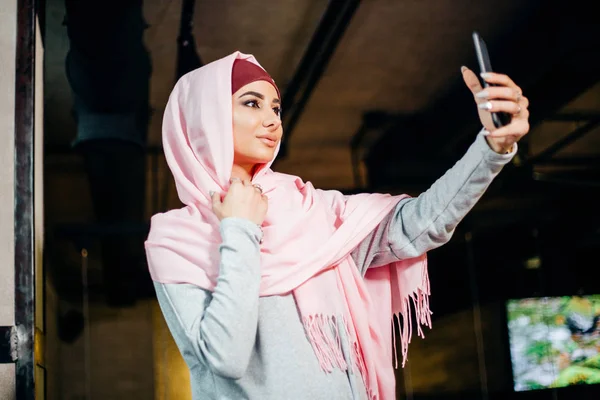 Портрет молодой привлекательной женщины в хиджабе, делая selfie фото на смартфоне Стоковое Фото