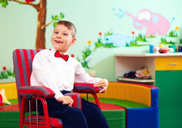 Милый Счастливый ребенок в инвалидной коляске, носить Глэд тряпки в центре для детей с особыми потребностями — стоковое фото
